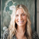 A natural light portrait of a smiling woman with wavy blonde hair for professional branding.