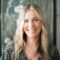 A natural light portrait of a smiling woman with wavy blonde hair for professional branding.